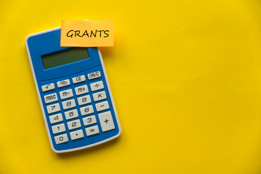 a calculator with a sticky note attached that says 'grants'