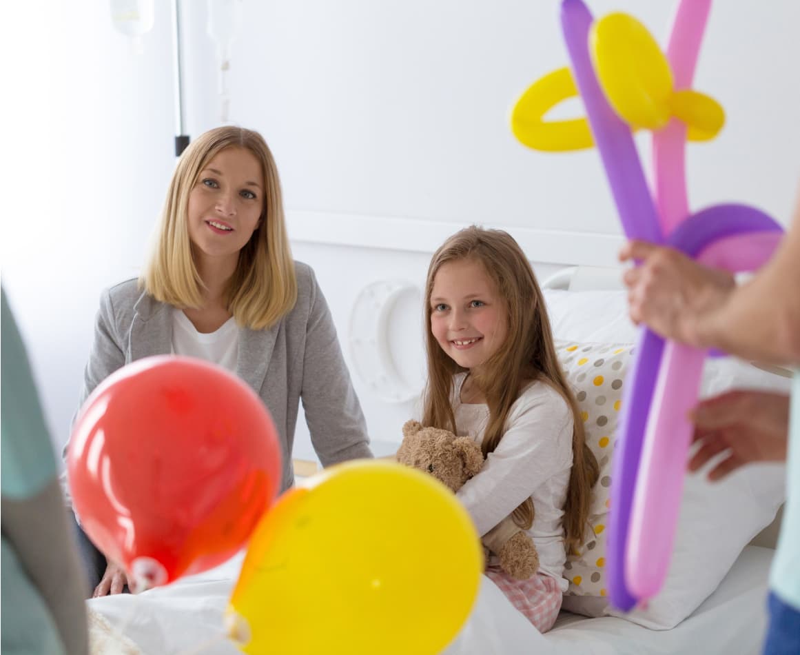 Volunteers visiting a children's ward in the hospital with balloons.