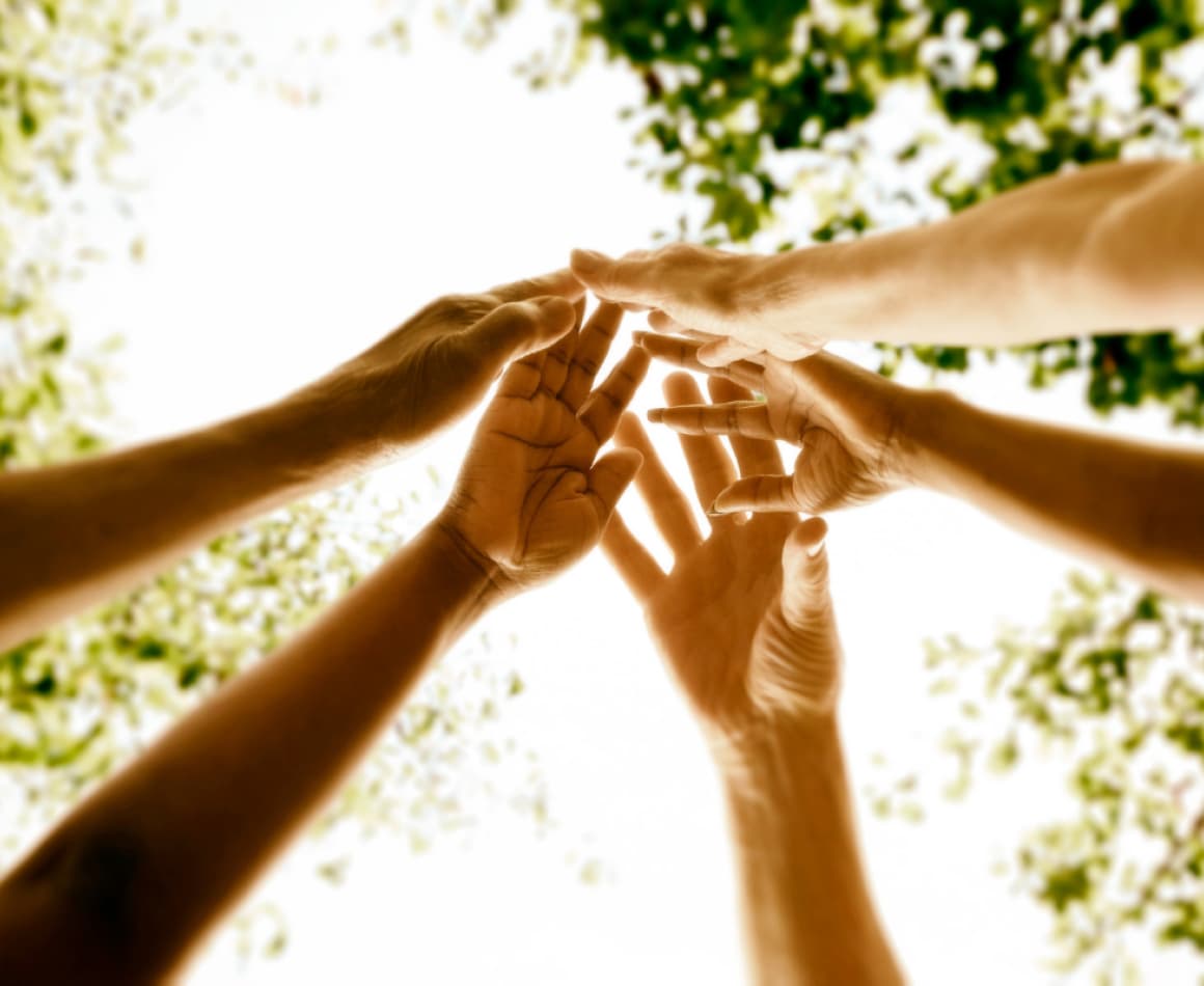 Group of people joining hands in the air. 