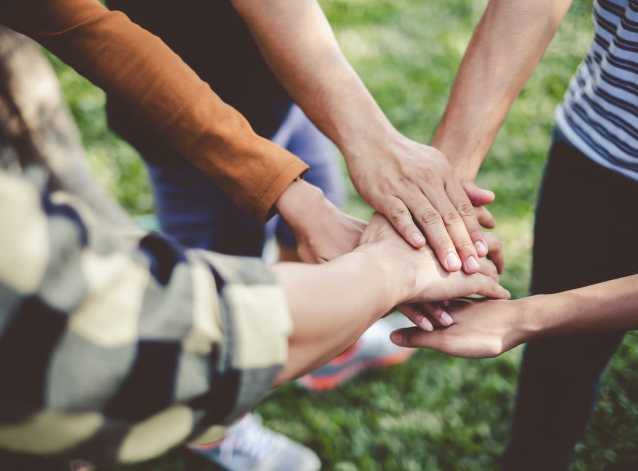 Group of people joining hands in a huddle. 