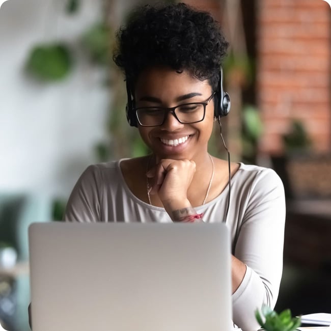 Woman wearing headphones watching something on her laptop.