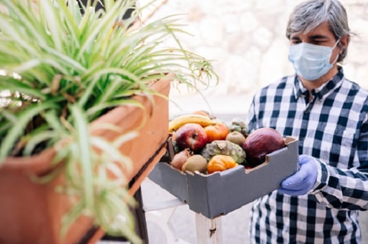 Man wearing masking with basket of fruit